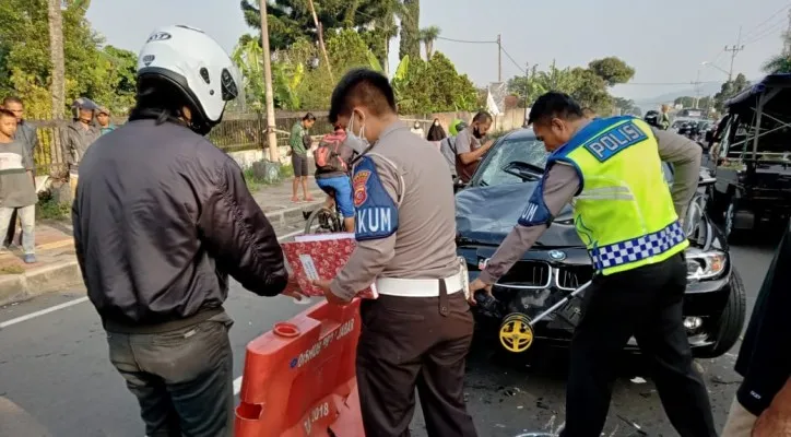 Anggota Laka Polres Bogor melakukan olah TKP di lokasi kecelakaan mobil BMW tabrakan beruntun di Jalan Puncak, Bogor. (Foto/Ist)