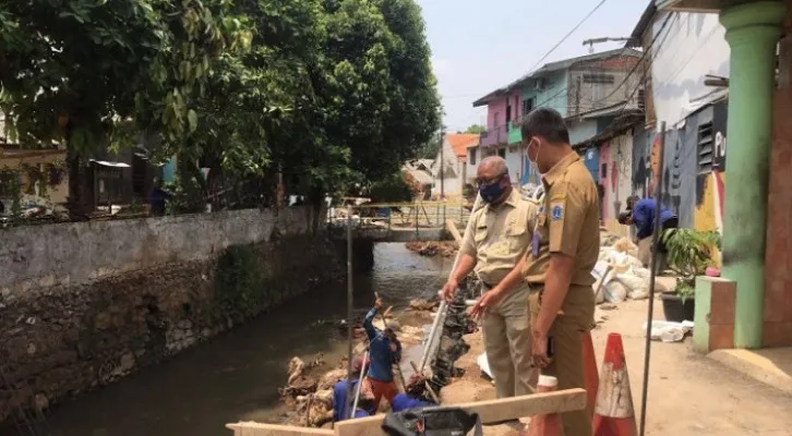 Petugas Kelurahan Lebak Bulus menindaklanjuti adanya penurunan tanah dengan  menutupi tanah turap yang mengalami penurunan yang berpotensi longsor di Kali Grogol, Lebak Bulus, Cilandak, Jaksel. (ist)