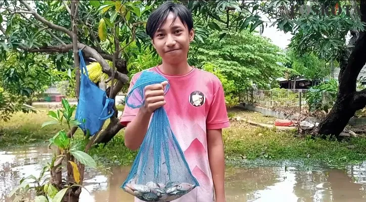 Farhan (16) warga kampung Rawa Bogo Jati mekar RT 002 RW 017, saat mencari ikan di tengah genangan air yang telah surut di perumahan Bumi Nasio Indah Jatiasih. Selasa (02/11/2021) siang. (Foto/Poskota.co.id/Ihsan Fahmi)