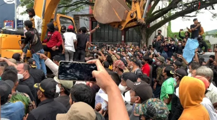 Pengunjuk rasa saat menyandera beko yang akan membongkar bangunan tempat hiburan malam. (foto: poskota/haryono)