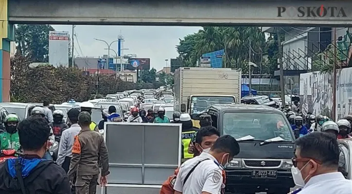 Petugas gabungan lakukan kanalisasi dalam penerapan ganjil genap depan Terminal Depok Metro stater macet panjang. (foto: Angga)