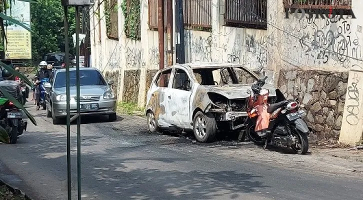 Sisa bangkai Mobil Ayla yang habis terbakar masih terpajang di tempat kejadian menganggu kendaraan Umum yang melintas di tanjakan Jalan Curug Agung. (Angga)