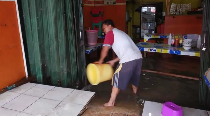 Subur sedang membersihkan tokonya yang terdampak banjir. (Foto luthfi)