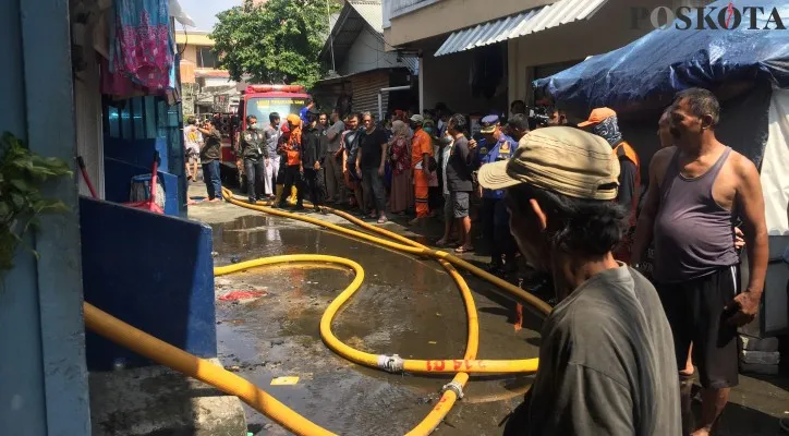 Petugas Damkar dibantu warga memadamkan api yang membakar 1 rumah di Kelapa Gading Timur. (foto: poskota/ ivan)