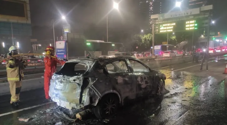 Petugas Damkar bersama Sat PJR dan Ditlantas Polda Metro Jaya memadamkan api yang membakar satu unit mobil SUV mini di Jalan Tol Dalkot arah Cawang pada Rabu 11 Mei 2022 malam. (foto: dok. ditlantas pmj)