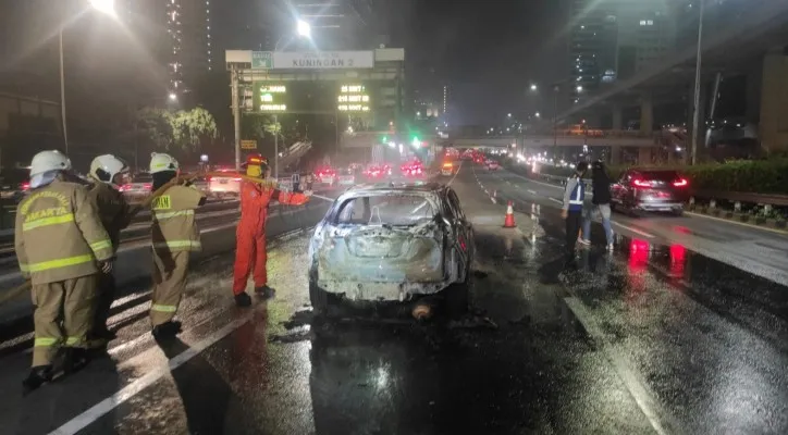 Petugas Damkar bersama Sat PJR dan Ditlantas Polda Metro Jaya memadamkan api yang membakar satu unit mobil SUV mini di Jalan Tol Dalkot arah Cawang pada Rabu 11 Mei 2022 malam. (foto: dokumentasi ditlantas pmj)