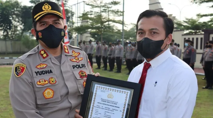 Kapolres Serang AKBP Yudha Satria saat menyerahkan penghargaan kepada Kasatreskrim AKP Dedi Mirza di lapangan Mapolres Serang. (foto: ist)