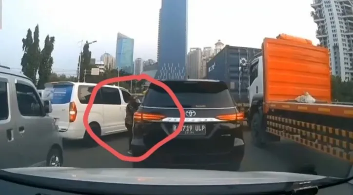 Seorang pria nekat menggasak spion mobil Toyota Fortuner yang terjebak kemacetan di Jakarta Barat. (foto: ist)