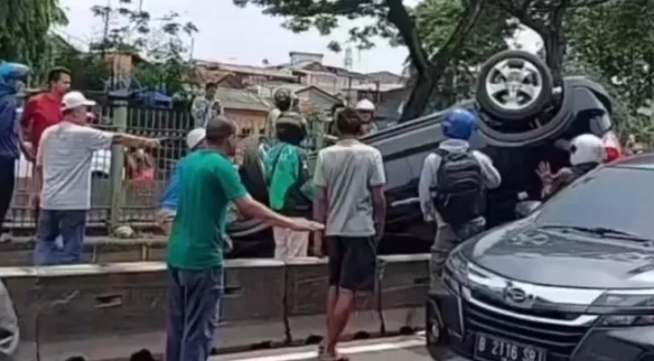 Sejumlah pengendara dan warga sekitar mencoba mengevakuasi mobil minibus yang berada dalam posisi terbalik usai mengalami insiden laka lantas tunggal di Kawasan Pasar Rumput Setiabudi, Jakarta Selatan.(Foto: Tangkapan layar video)