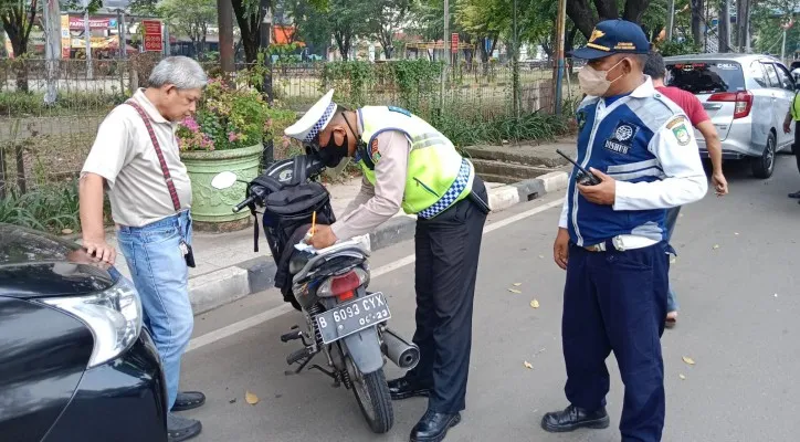 Petugas Polres Metro Tangerang Kota  saat menindak pemotor yang tak menggunakan helm. (foto: ist)