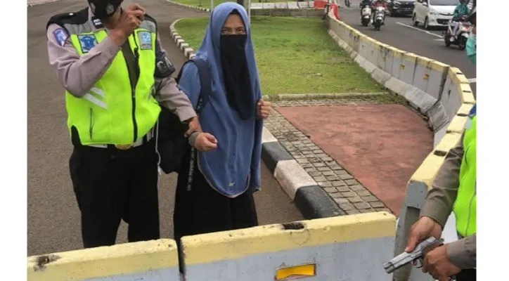 Polisi menangnani Wanita bercadar hitam yang nekat menerobos istana presiden sambil membawa senpi lalu menodong ke anggota Paspampres. (Ist)