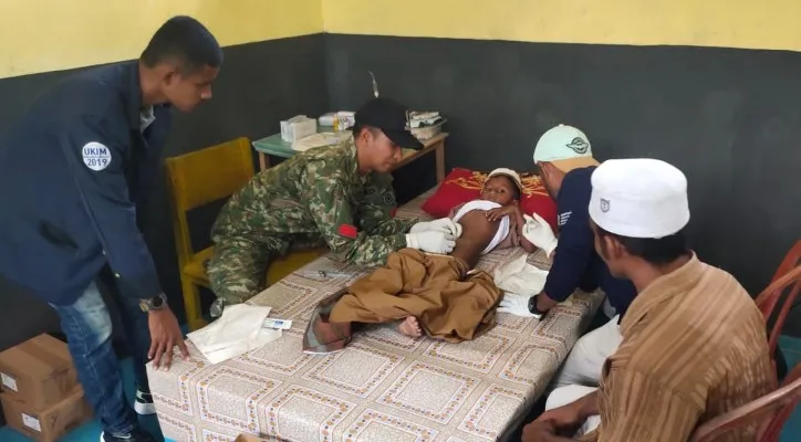 Seorang prajurit TNI sedang mengkhitan seorang anak.(Penerangan Satgas Yonarmed 1 Kostrad)