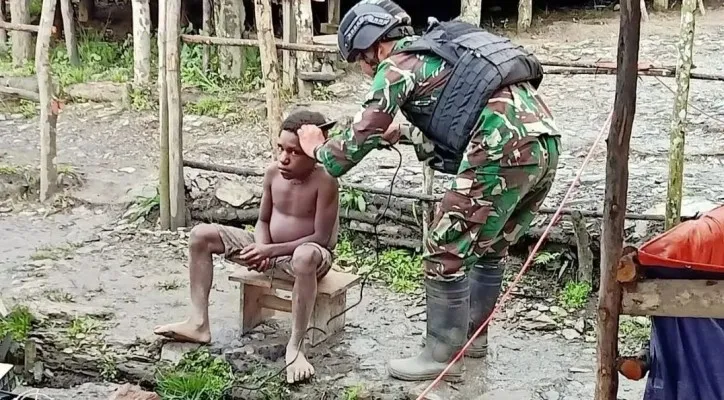 Seorang prajurit dari Satgas Yonif Raider 303/SSM mencukur rambut seorang anak Wombru Papua.(Penerangan Kostrad)