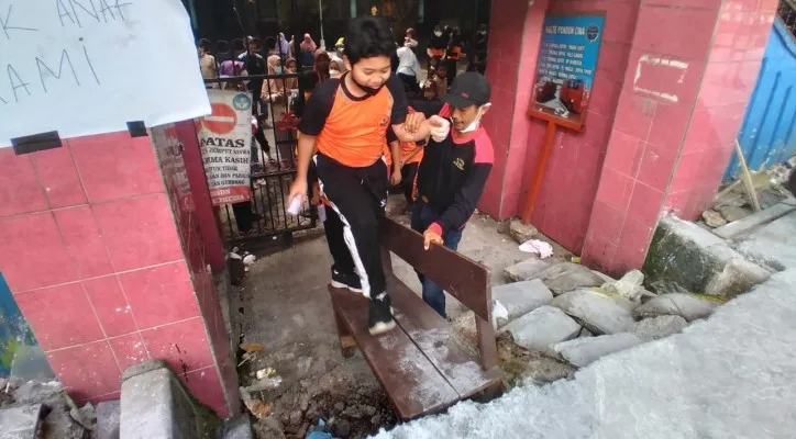 Anak-anak pelajar SDN Pocin 1 Beji Kota Depok, kesulitan untuk bisa masuk sekolah harus dibantu kursi karena tertutup pengecoran proyek revitalisasi trotoar margonda. (Foto: Angga)