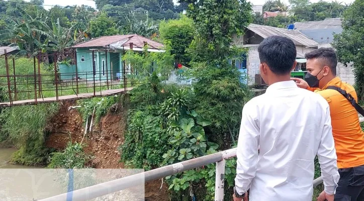 Tebingan tanah di bawah jembatan berusia 50 tahun longsor mengakibatkan akses dua desa di Kabupaten Bogor terputus. (foto: ist)