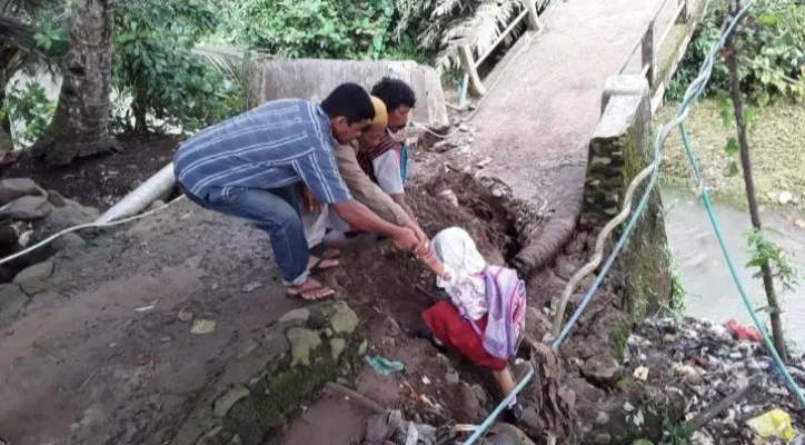 Sejumlah warga Jiput Pandeglang saat membantu siswa naik di jembatan yang ambruk.(Ist)