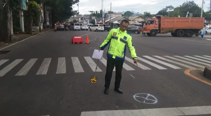 Petugas Satlantas Polres Bogor saat menunjukan lokasi kecelakaan yang melibatkan sepeda motor dan truk tronton di Jalan Raya Jakarta-Bogor. (foto: ist)