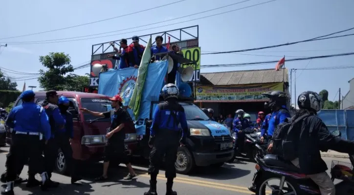 Massa buruh saat melakukan konvoi di Jalan Raya Serang menuju Kantor Disnaker Kabupaten Tangerang. (foto: poskota/veronica)