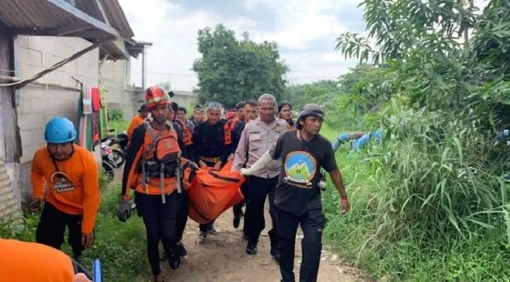 Petugas SAR saat mengevakuasi jasad Junaedi (14) yang tertabrak kereta lalu tenggelam di kali Cilemah Abang, Bekasi. (Ist).