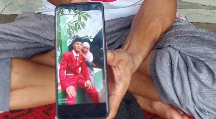 Effendi kakak pertama korban mayat dalam karung menunjukan foto semasa hidup adiknya Lulu bersama dengan anak pertama akmal (18) waktu kelulusan sekolah madrasah. (Foto: Angga)