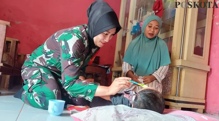 Babinsa Koramil Kramatwatu, Sertu Kowad Deka saat menyuapi anak stunting di Desa Toyomerto, Kabupaten Serang. (Foto: poskota/Bilal)