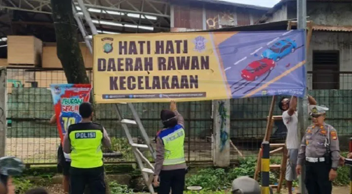 Kasubnit Kamsel 1 Iptu Sally bersama Kanit Lantas Polsek Bojongsari AKP Suharto dengan anggota memasang spanduk imbauan Hati-Hati Daerah Rawan Kecelakaan di Jalan Raya Bojongsari, Depok. (Foto: Angga)