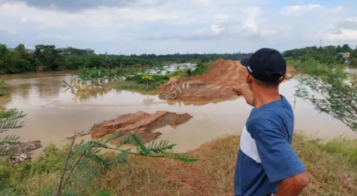 Ketua RT  di Kp Cikangkung, Desa Nagara, Sarila saat menunjukan tanggul yang dihantam air sungai Ciujung (foto: poskota/bilal)