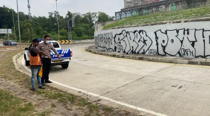 Teks Foto: Petugas Laka dengan penjaga tol menunjukan lokasi mobil terjun bebas dari ujung jalan Tol Desari-Sawangan belum tersambung. (ist)