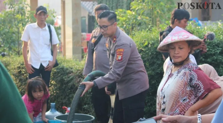 Teks Foto:Kapolsek Bojongsari Kompol Aruan turun langsung mendistribusikan air bersih ke warga Parung Poncol Bojongsari dalam bakti sosial langsung diserbu warga. (Angga)