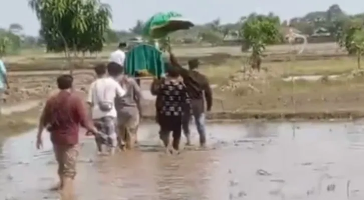 Teks Foto: Rombongan pengantar jenazah lewat sawah di Muaragembong. (ist)