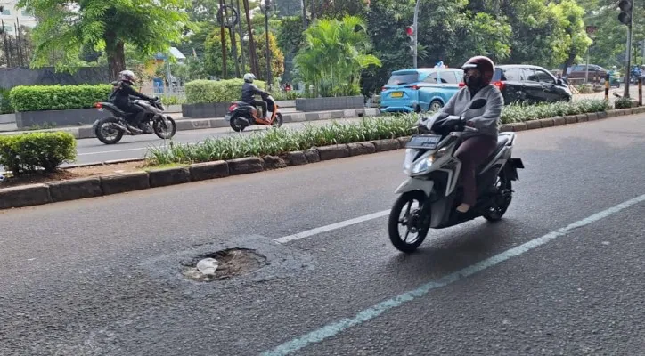 Pengendara sepeda motor menghindari lubang saat melintas di Jalan Chairil Anwar, Kota Bekasi. (Ihsan Fahmi).