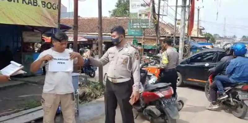 Anggota memberika  sanksi sosial kepada warga tidak bermasker dengan mengalungi papa  pelanggar PPKM menjadi pusat perhatian warga melintas. (ist)