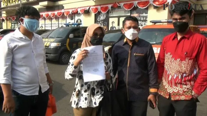 PDY (pakai kerudung) didamping kuasa hukumnya saat menunjukan surat laporan polisi di depan Mapolres Metro Jakarta Utara. (foto: yono)