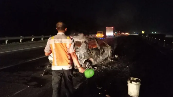 Petugas patroli Astra Infra Toll Road saat mendinginkan kendaraan vios yang hangus terbakar. (ist)