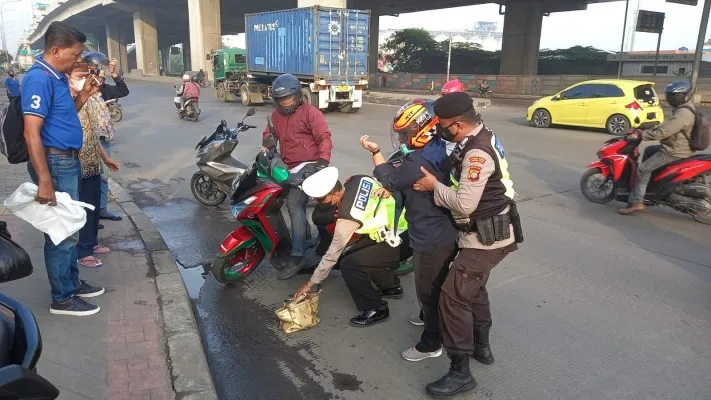 Personil Polsek Koja saat membantu pengendara motor yang terjatuh. (Ist)