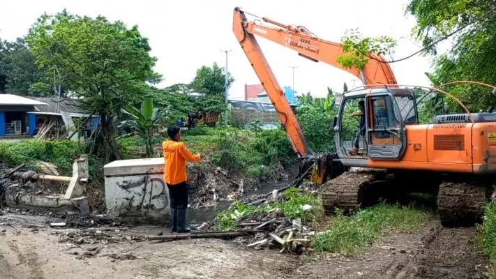 Petugas DLH Kabupaten Bekasi mengerahkan alat berat angkut sampah di Kali Jambe. (Ist)