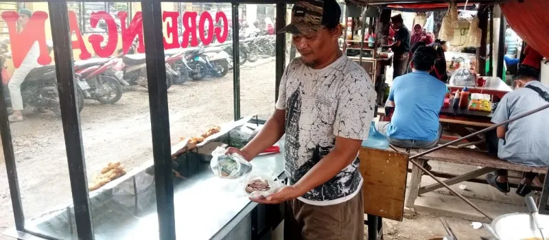 Pedagang gorengan di Bekasi saat menunjukan uangnya yang rusak dimakan rayap. (Ist)