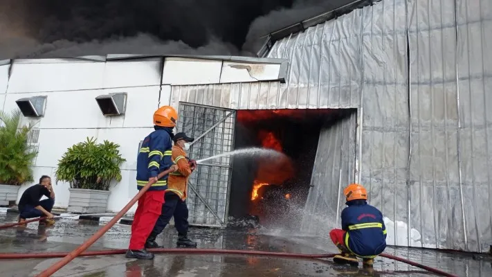 Petugas Damkar Kabupaten Bekasi memadamkan api yang membakar pabrik cat . (Ist)