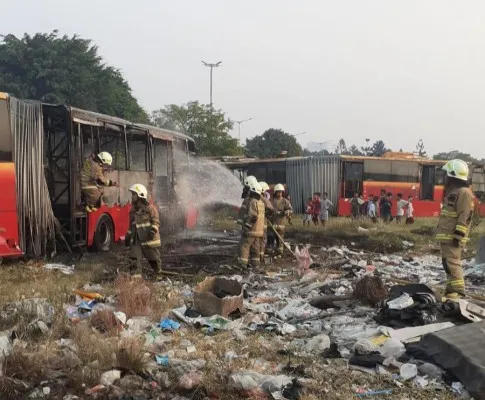 Petugas memadamkan api yang membakar bangkai TransJakarta. Ist