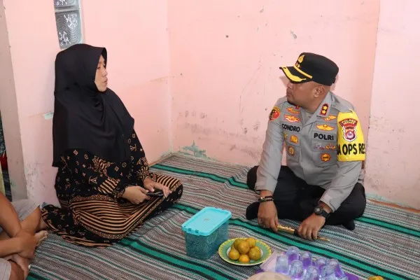 Kapolres Serang, AKBP Candra Sasongko saat berbincang dengan istri almarhum Budi Hermawan, anggota Linmas yang meninggal usai penghitungan suara Pemilu 2024. (foto: ist)