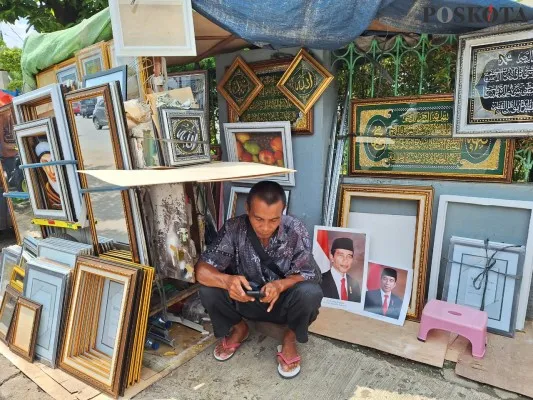 Pedagang figura di Pasar Proyek Bekasi saat menjaga lapak foto dan bingkai. (Poskota/Ihsan)