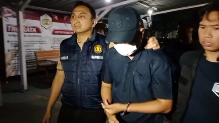 Pelaku pembunuhan jasad wanita dalam koper memakai topi digiring oleh Kepolisian Polsek Cikarang Barat. (Dok. Humas Polsek Cikarang Barat)