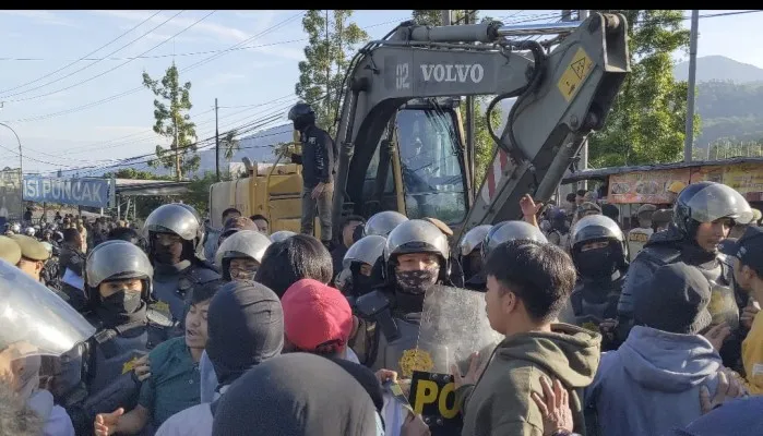 Warga mengadang alat berat yang hendak bongkar lapak PKL di Puncak Bogor (Poskota/Panca Aji)