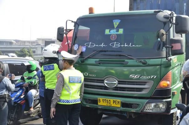 Petugas kepolisian saat menempelkan stiker aktivitas operasi patuh jaya 2024 di Jalan Ahmad Yani, Kota Bekasi. (Dok : Poskota/Ihsan)