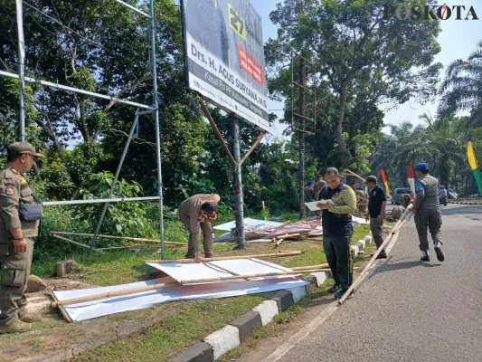 Satpol PP saat melakukan penurunan baliho Pilkada 2024 di wilayah Pemkab Tangerang. (Poskota/Veronica)