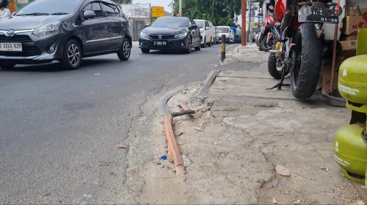 Kabel tanam fiber optik di Jalan Raya Kebon Jeruk, Jakarta Barat tampak menganga dikeluhkan warga. (Poskota/Pandi)