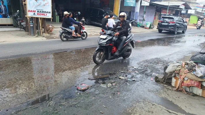 Pengendara motor melintasi jalan becek dan licin di Jalan Mangunjaya, Tambun Selatan, Kabupaten Bekasi, Sabtu, 23 November 2024. (Poskota/Ihsan)