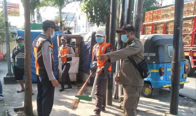 Petugas Satpol PP memberikan sanksi kerja sosial pada warga yang tak mengenakan masker saat melintas di Teluk Gong Raya, Kelurahan Penjaringan, Penjaringan, Jakarta Utara. (ist)