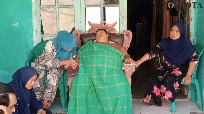 Rafka Adi Putra bocah obesitas 126 kilogram (pakai sarung) saat ditemui di rumahnya di Babelan Bekasi. (foto: poskota/ Ihsan).