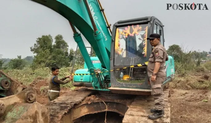 Foto : Anggota Satpol PP Kabupaten Tangerang saat melakukan penyegelan alat berat yang diduga menggali tanah secara ilegal. (Poskota/Veronica)